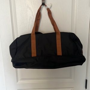 Black canvas duffel bag with bottom zip compartment